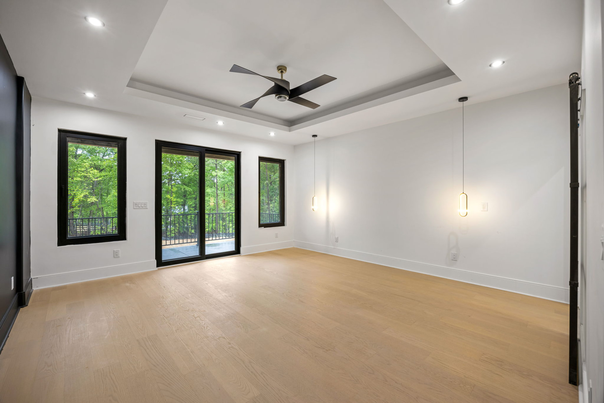 Primary bedroom with tray ceiling, deck access and brass pendants