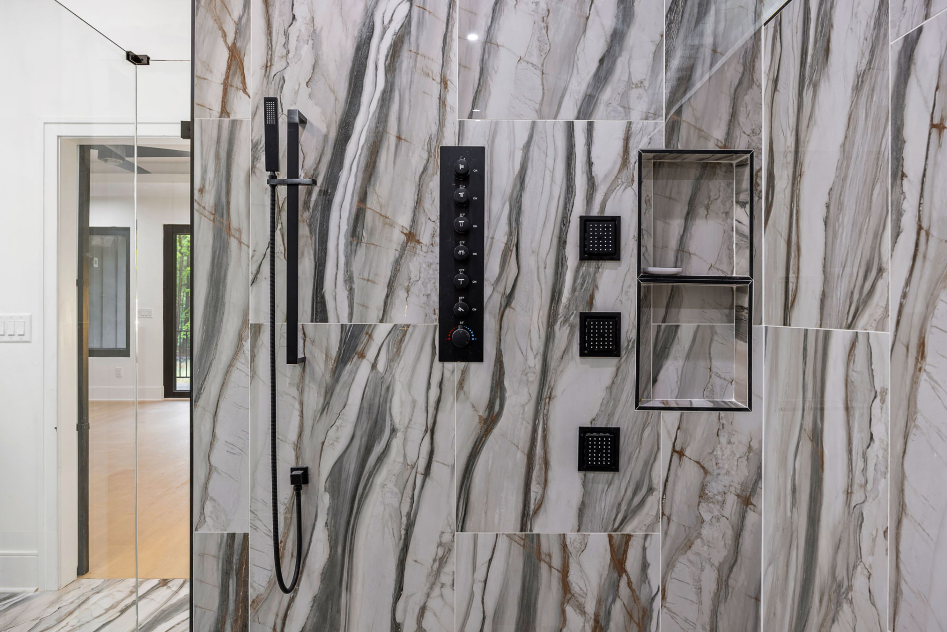 Marble shower wall with matte black digital shower controls and body jets