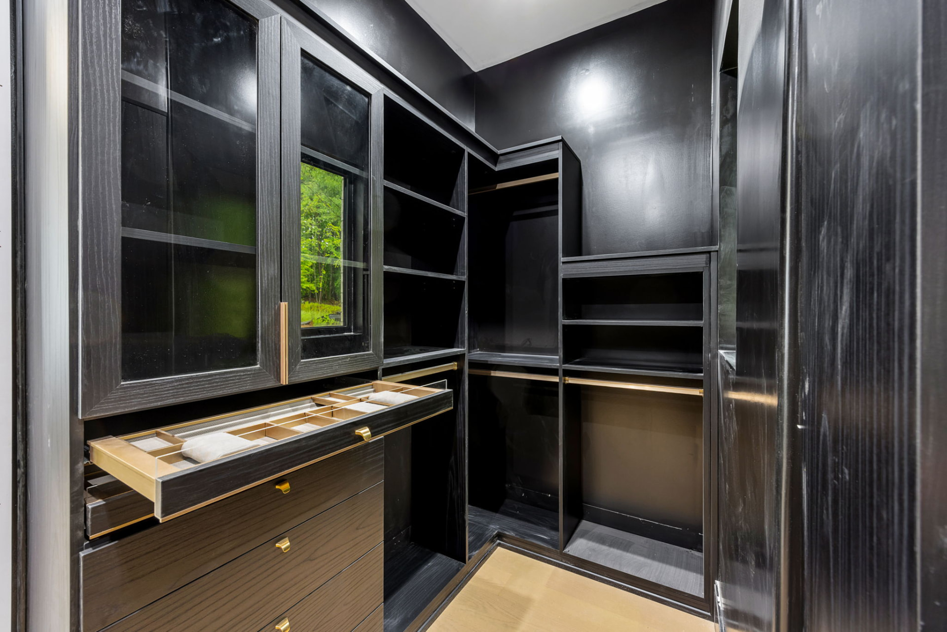 Custom black walk-in closet with brass hardware and jewelry drawer