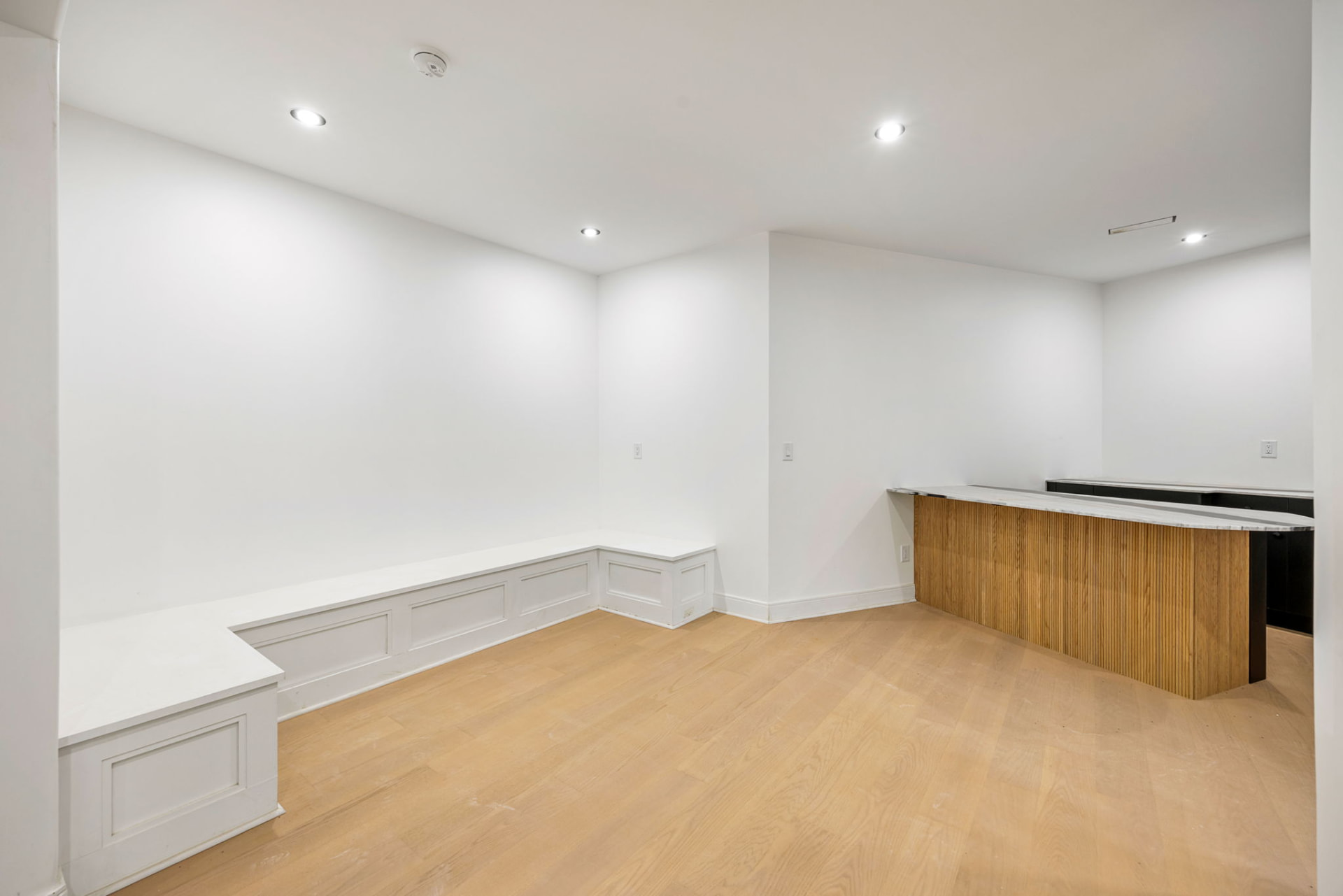 Lower level lounge with built-in bench seating and fluted oak bar