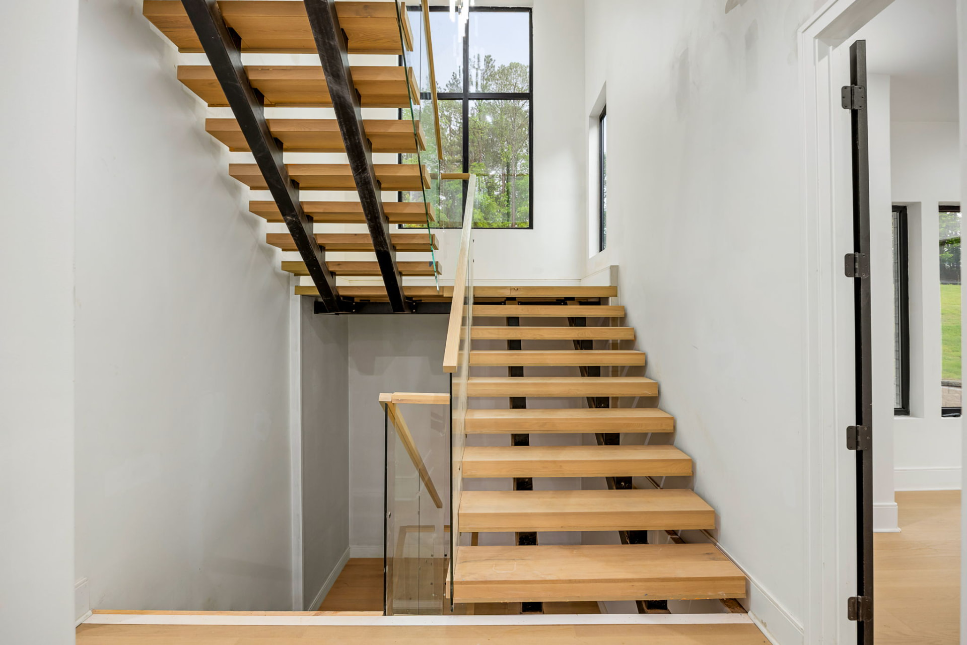 Floating white oak staircase with steel stringers and glass railing