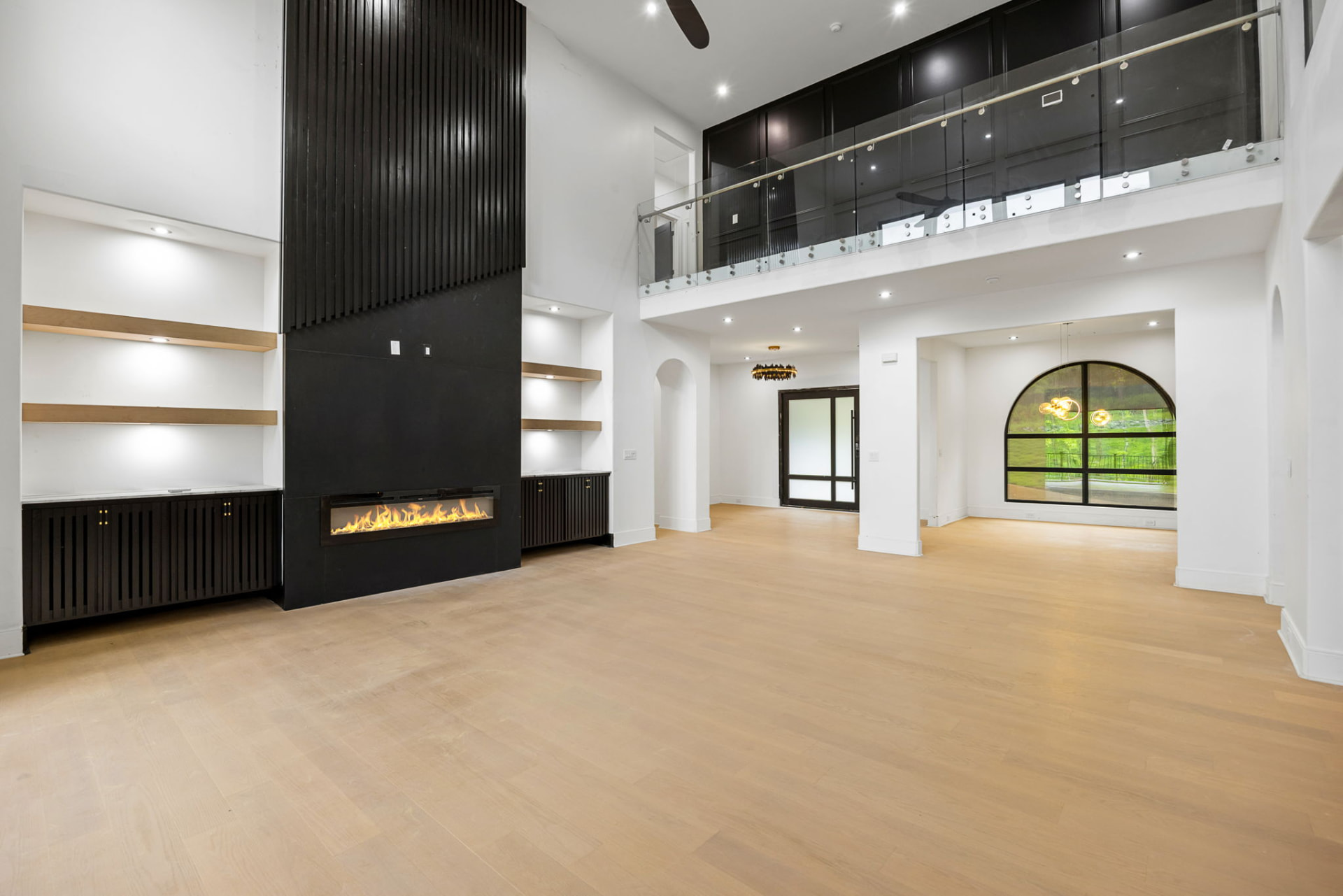 Great room with floor-to-ceiling black fireplace and floating oak shelves