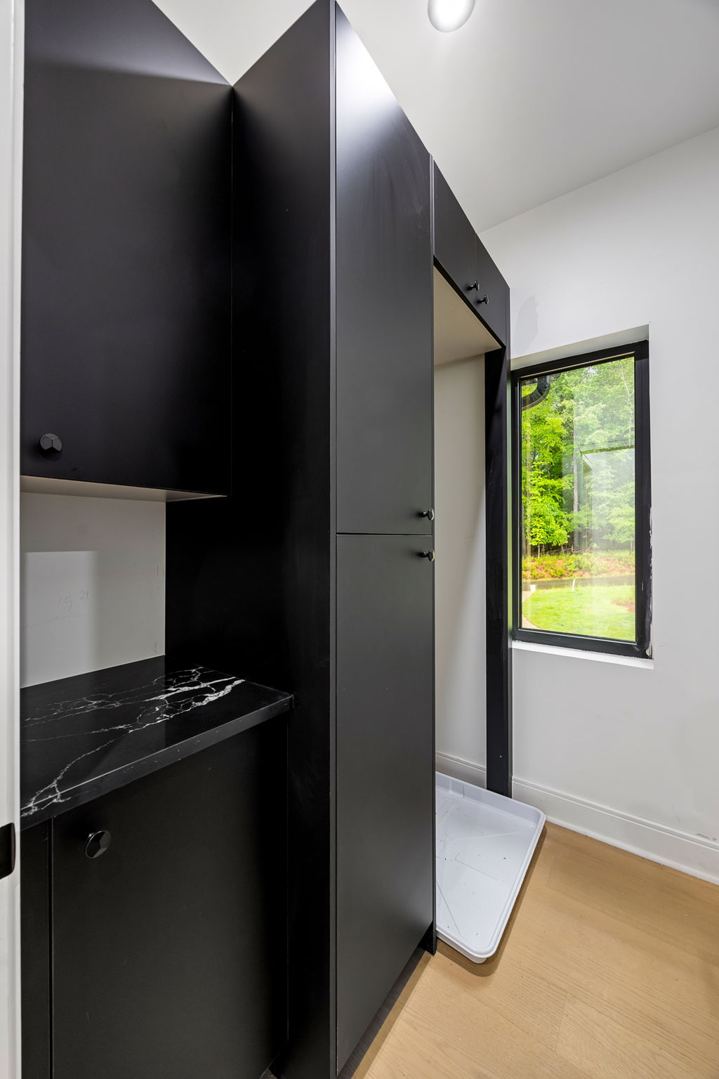 Mudroom with black cabinetry, marble counter and black-framed window