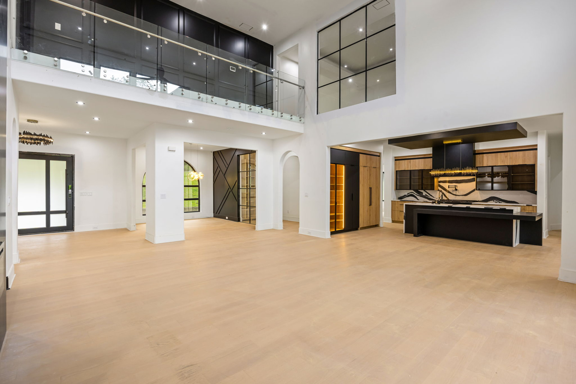Two-story great room with glass railing loft and black-and-wood kitchen