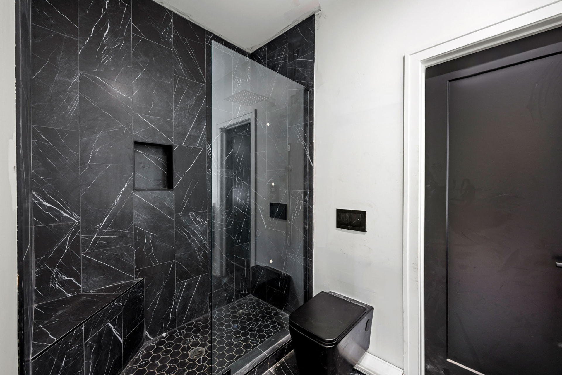 Black marble tiled shower with hexagon floor tile