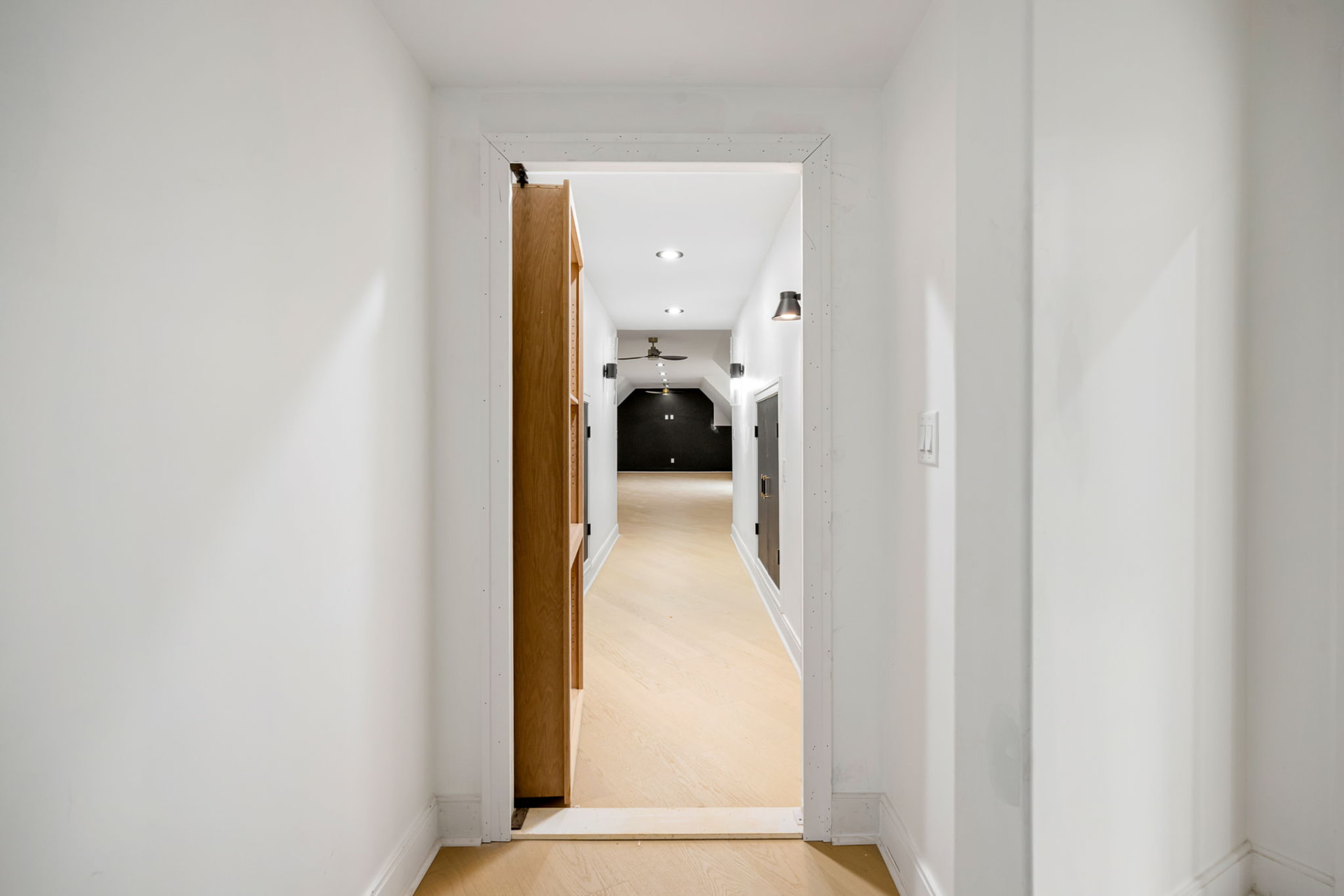 Hallway leading to a vaulted bonus room with black accent wall