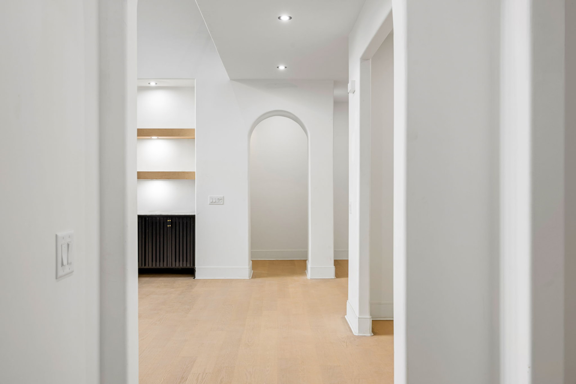 Arched hallway with built-in oak shelving and white oak floors