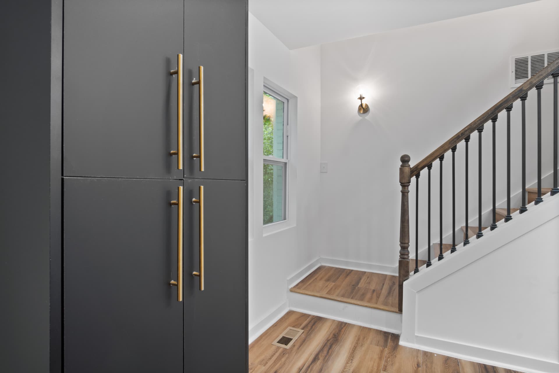Entry landing with charcoal pantry cabinetry and brass hardware