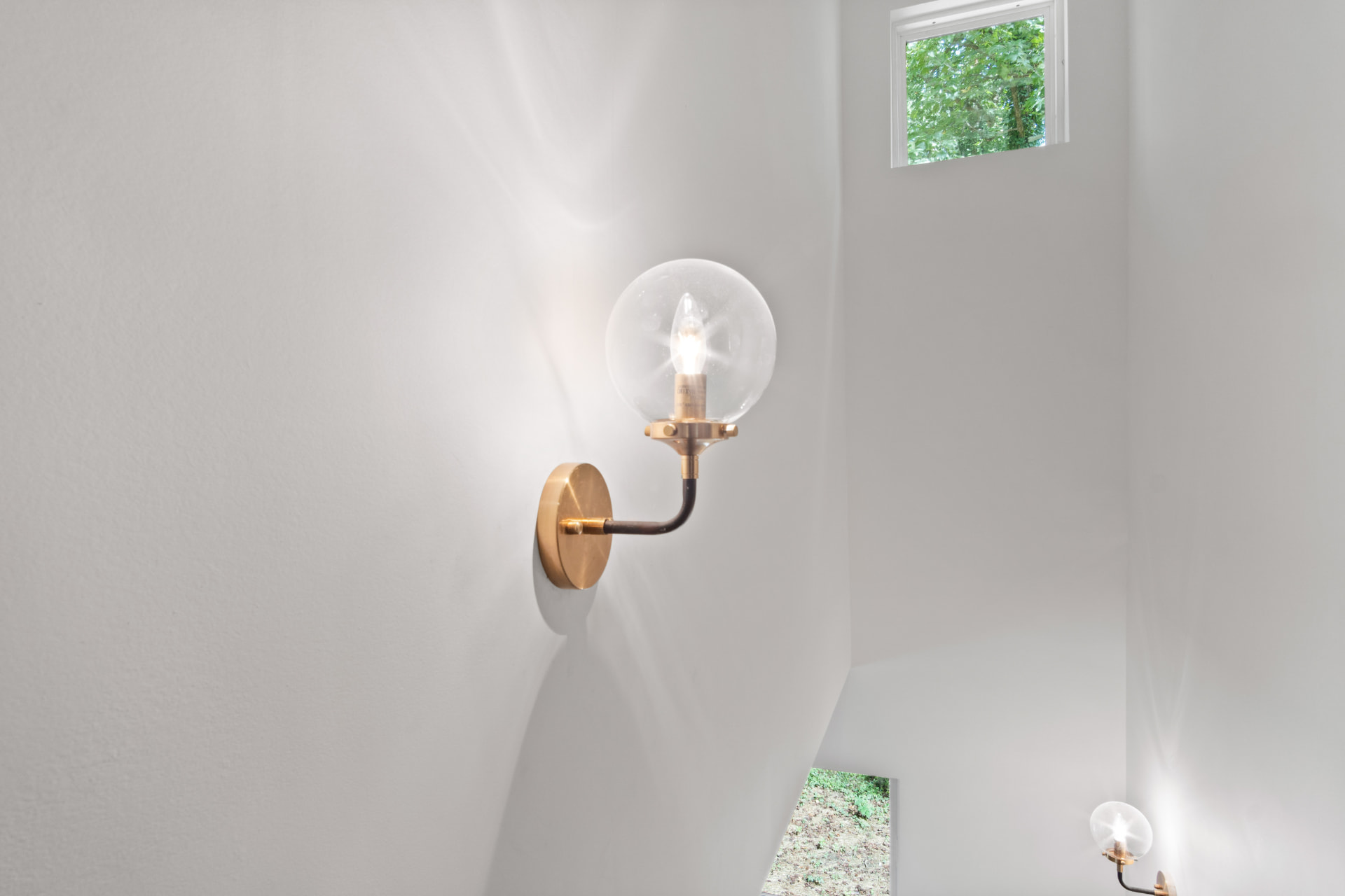 Brass and glass globe sconce on the stairwell wall