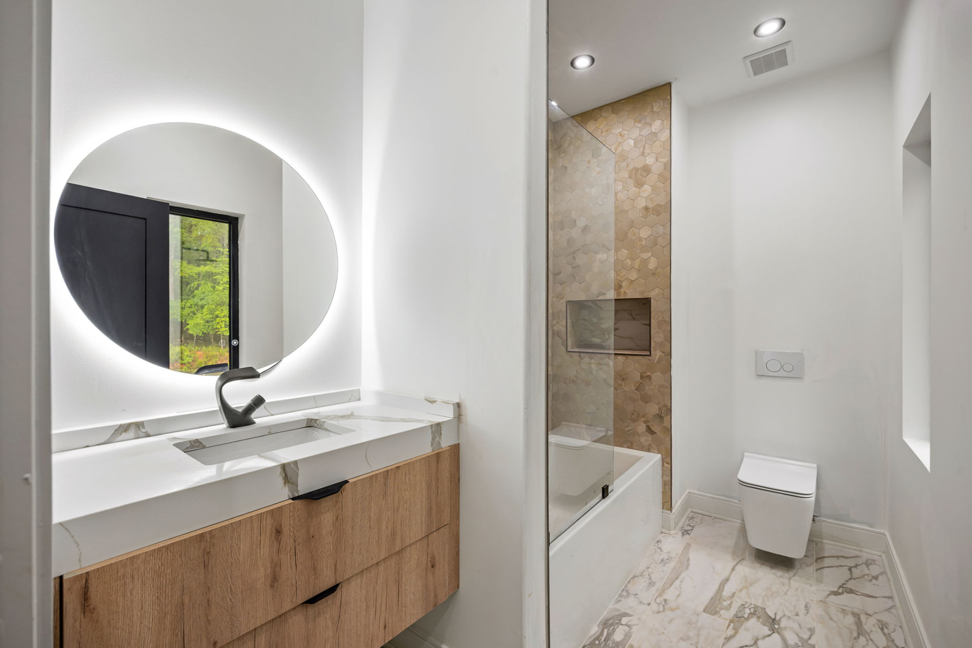 Guest bath with backlit mirror and hexagon tile shower surround