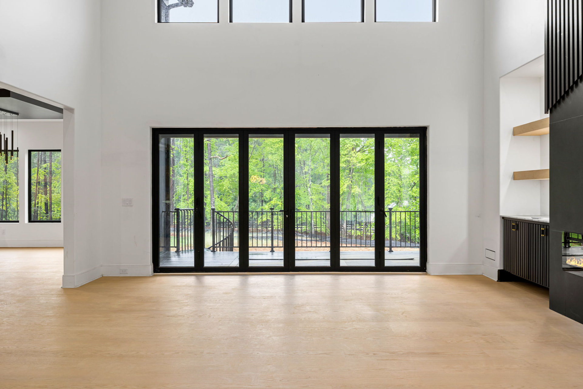 Great room folding glass wall framing the wooded rear deck