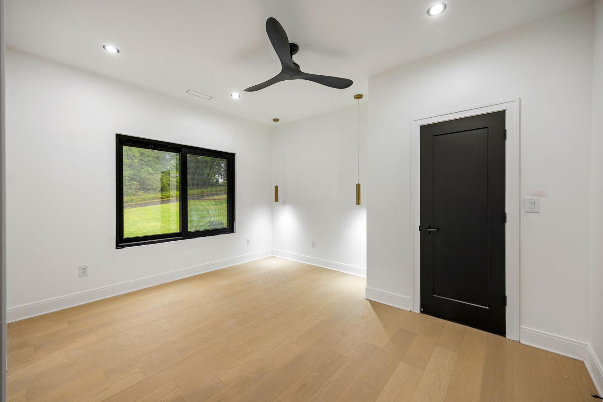 Bedroom with brass pendants, black door and wooded views
