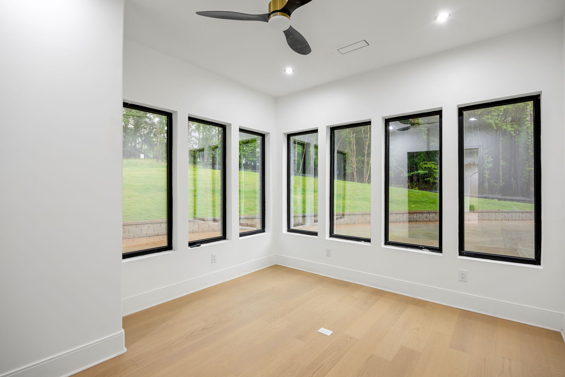 Sunroom with wraparound black-framed windows overlooking the lawn