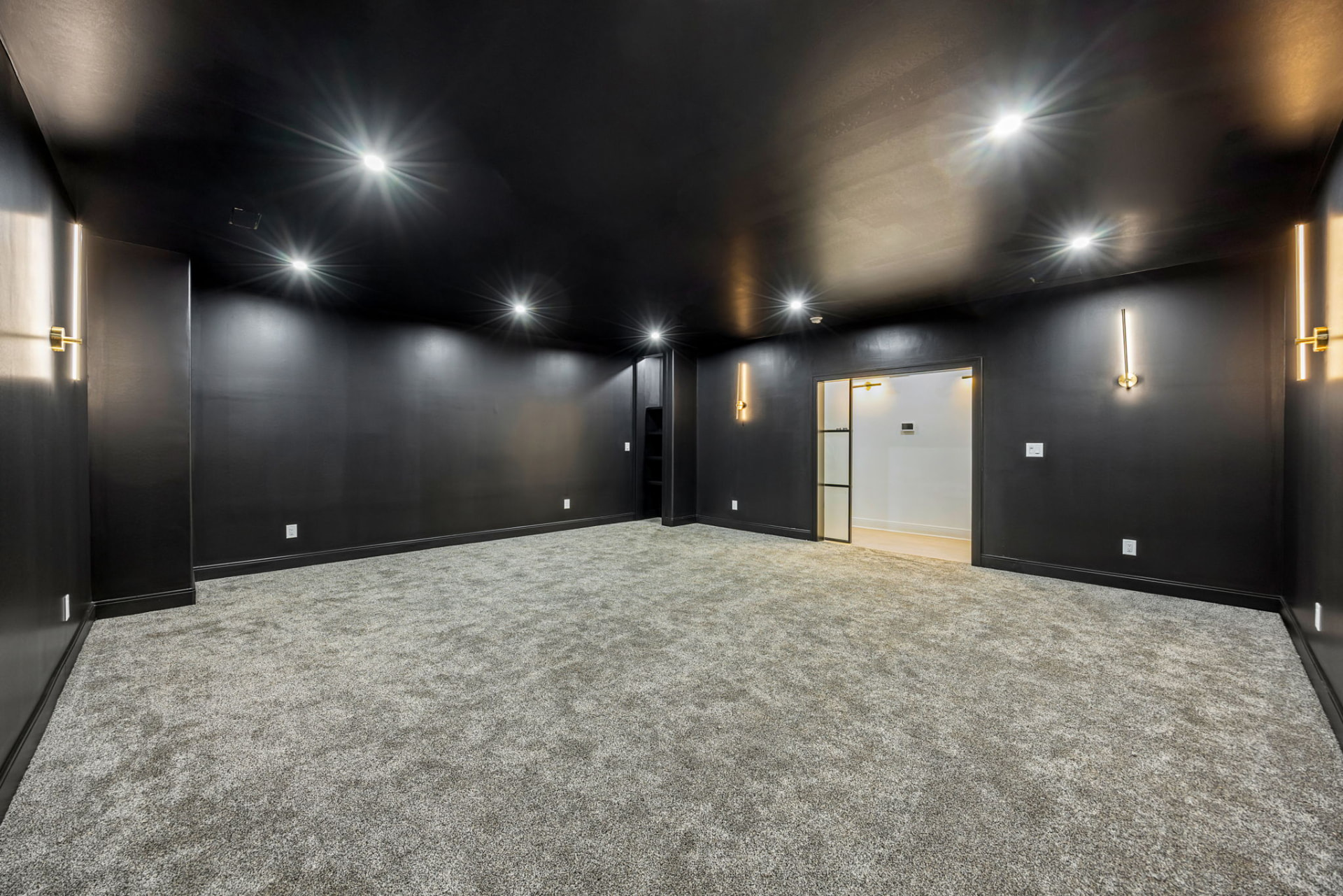 Home theatre with black walls, brass sconces and plush carpet
