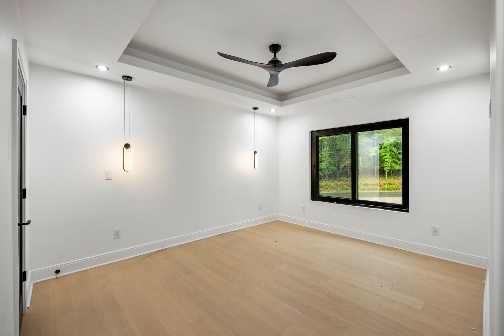 Bedroom with tray ceiling, pendant lighting and wooded views