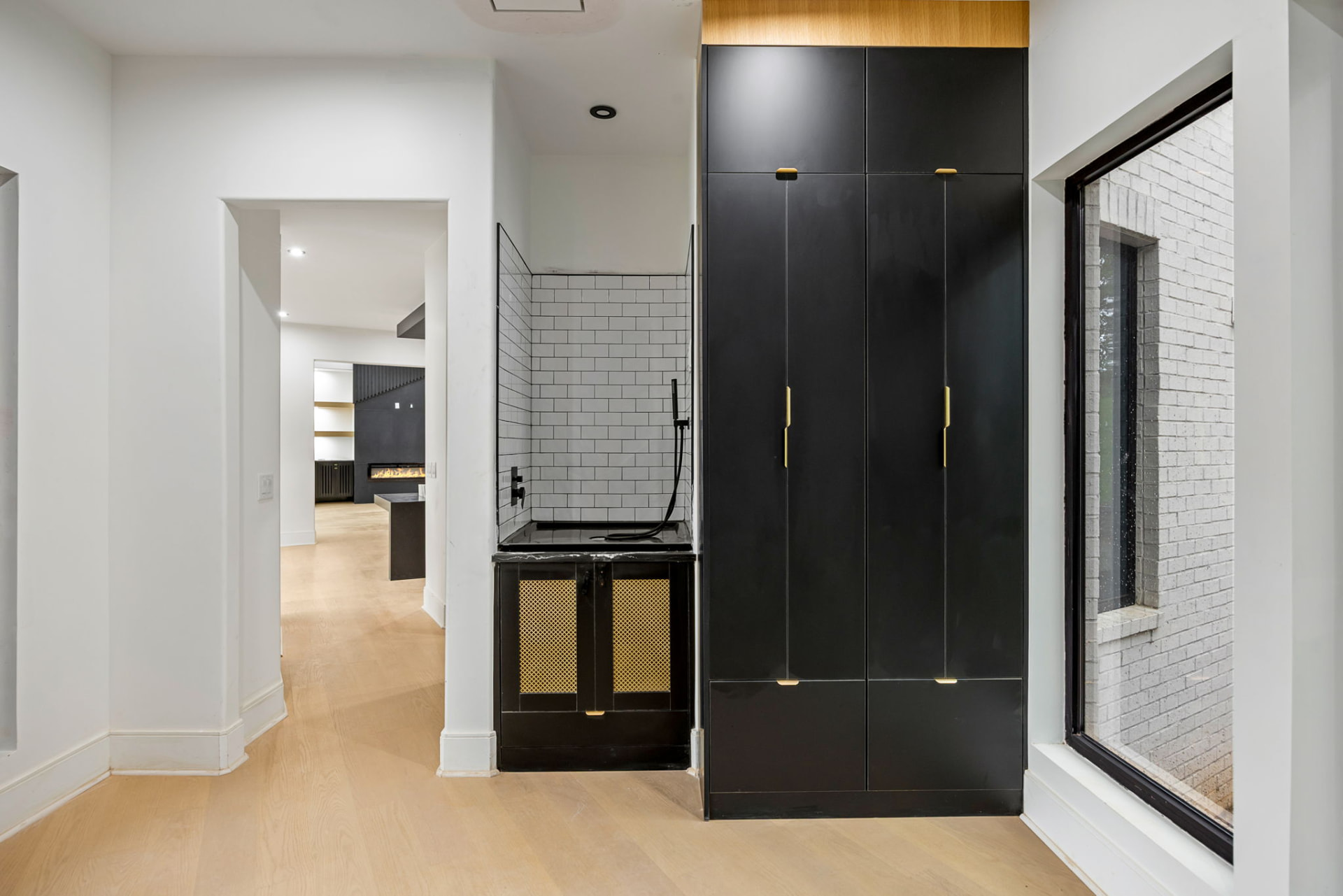 Entry hall with black cabinetry, brass hardware and tiled wet bar