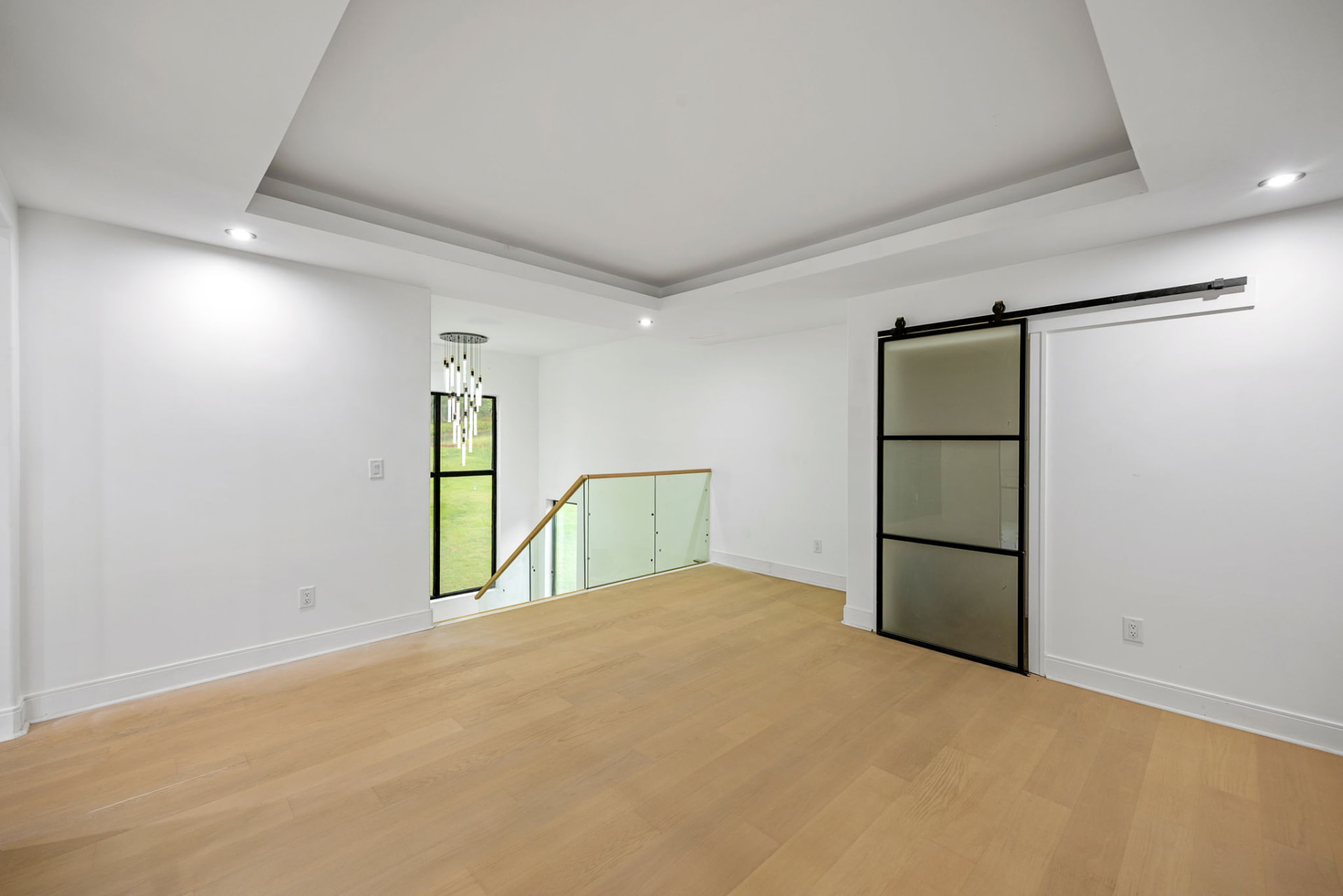 Upper-level loft with tray ceiling and frosted glass barn door