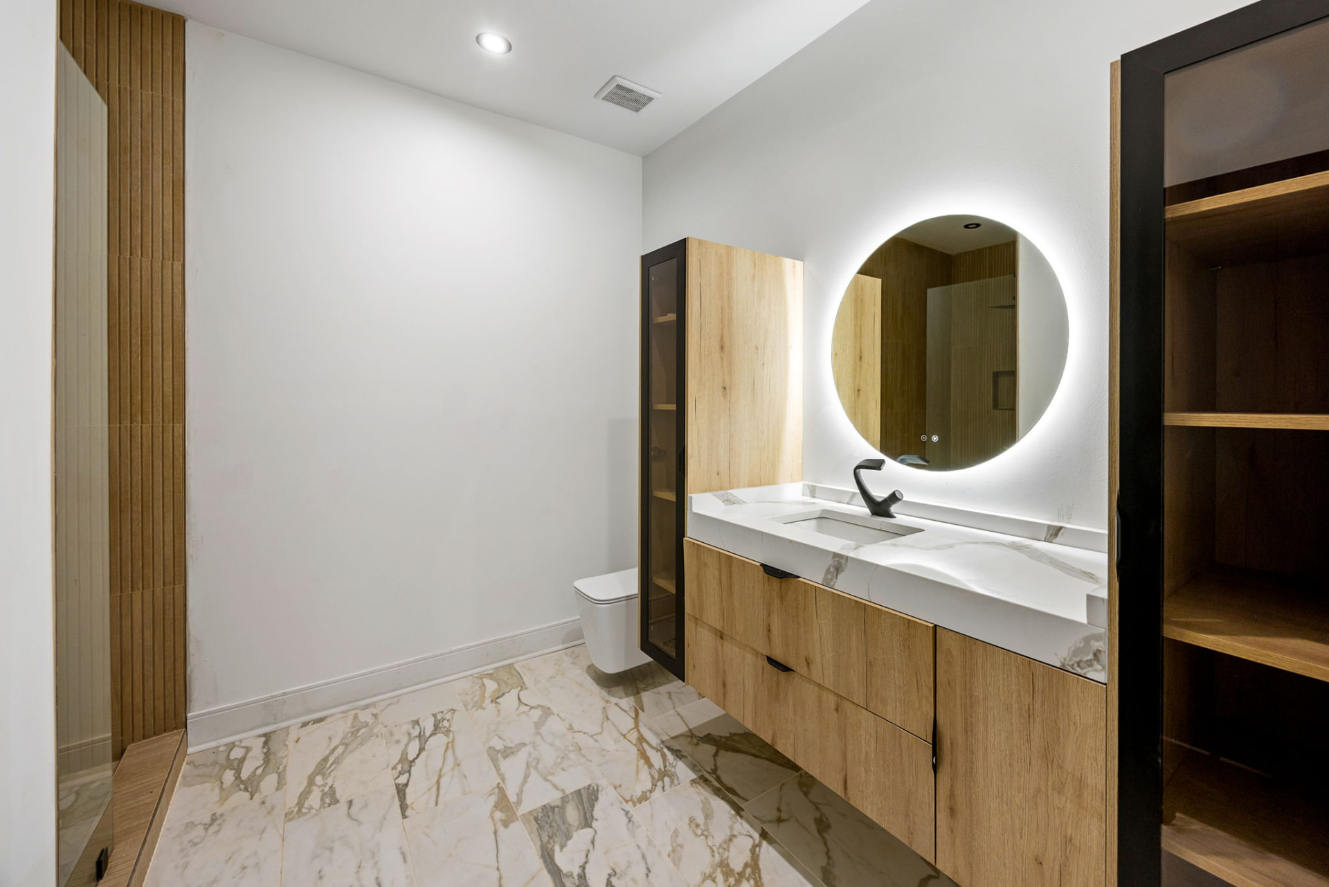 Powder bath with backlit round mirror and marble floors