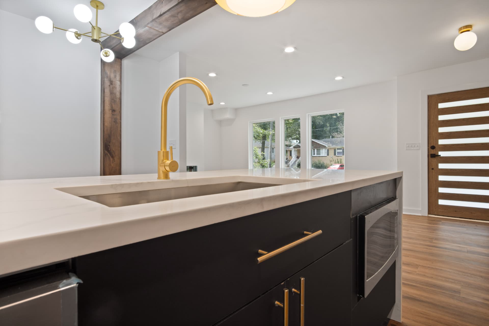 Island sink with brass faucet and front entry beyond