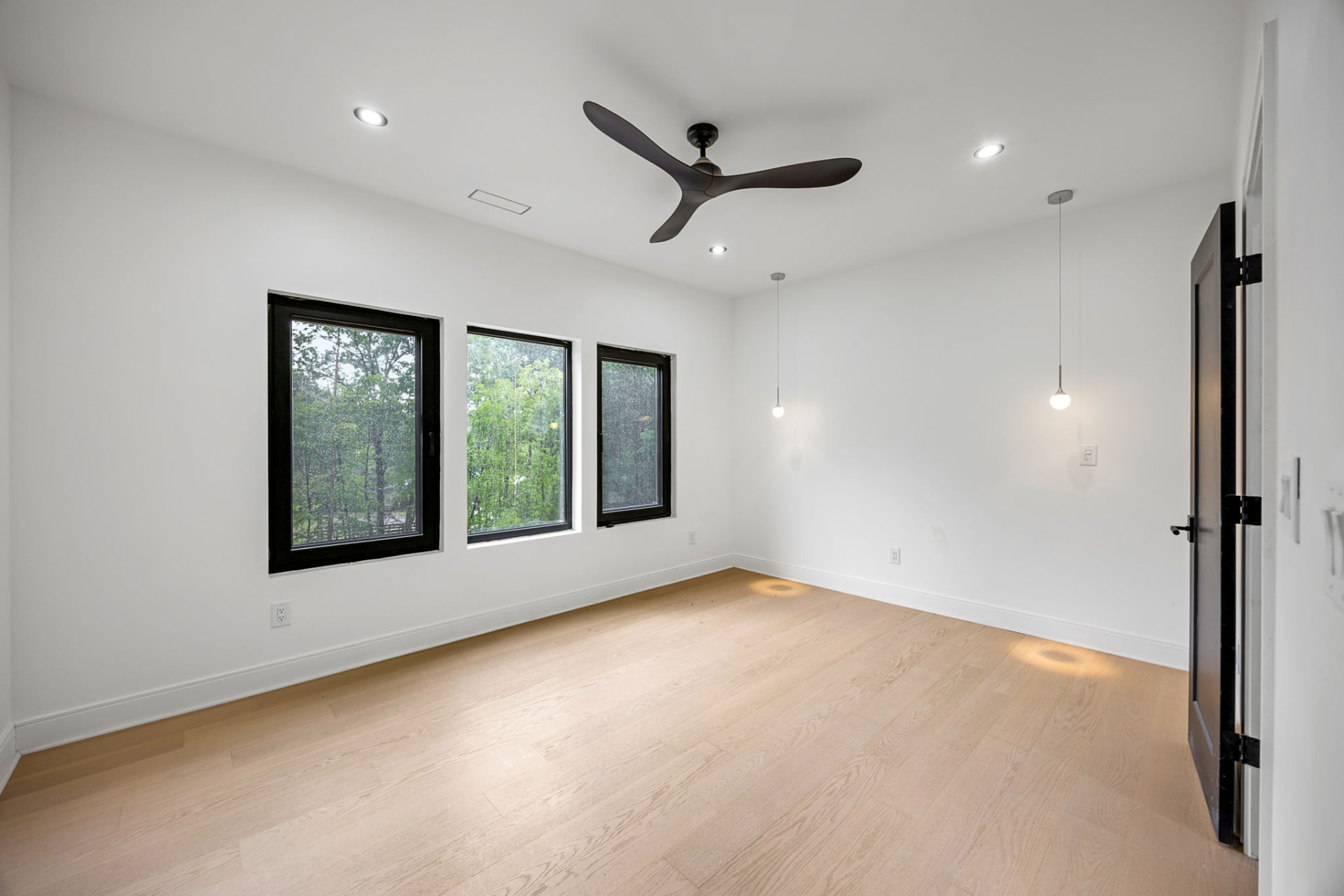 Bedroom with black-framed windows and globe pendants