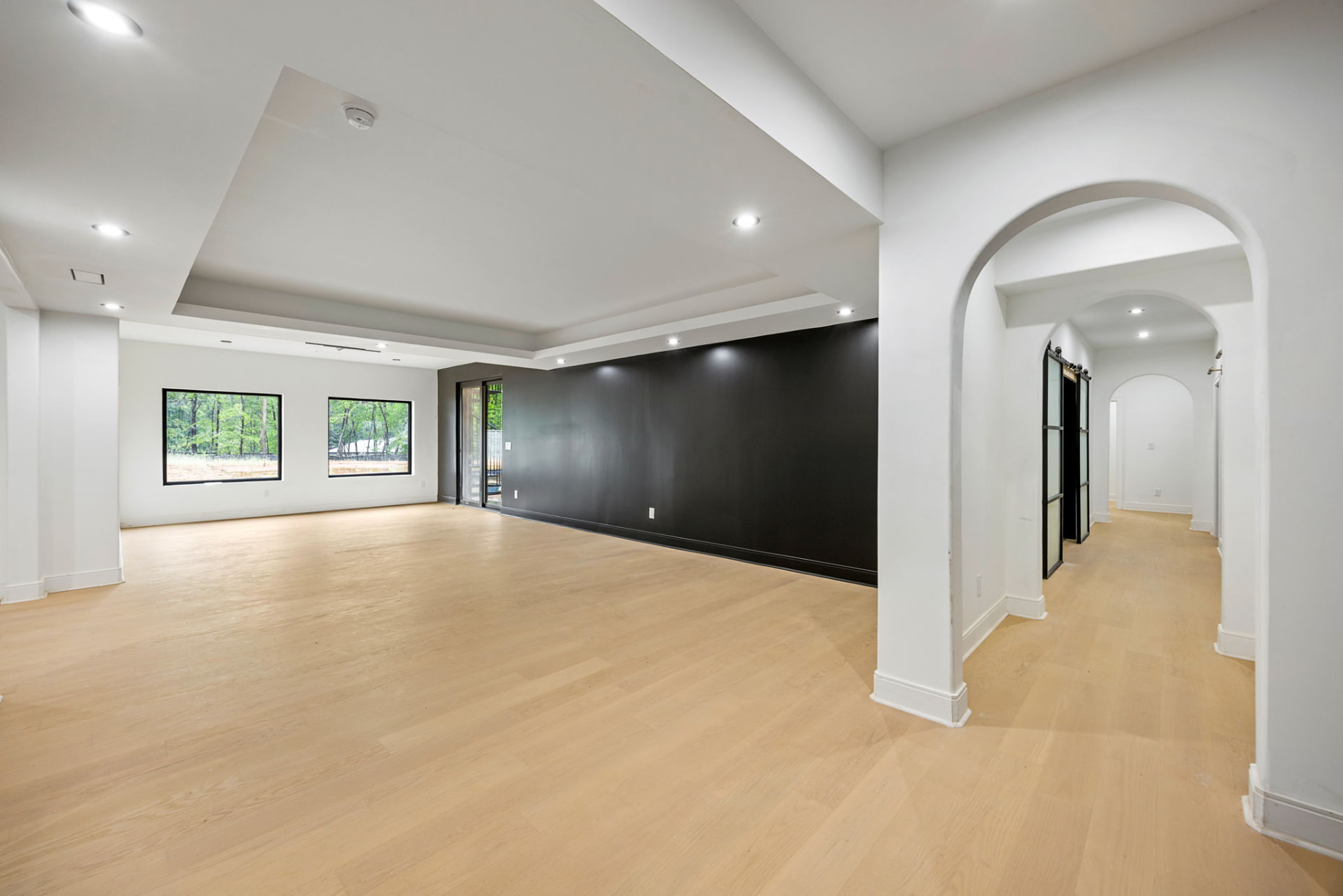 Lower level living area with black accent wall and arched openings