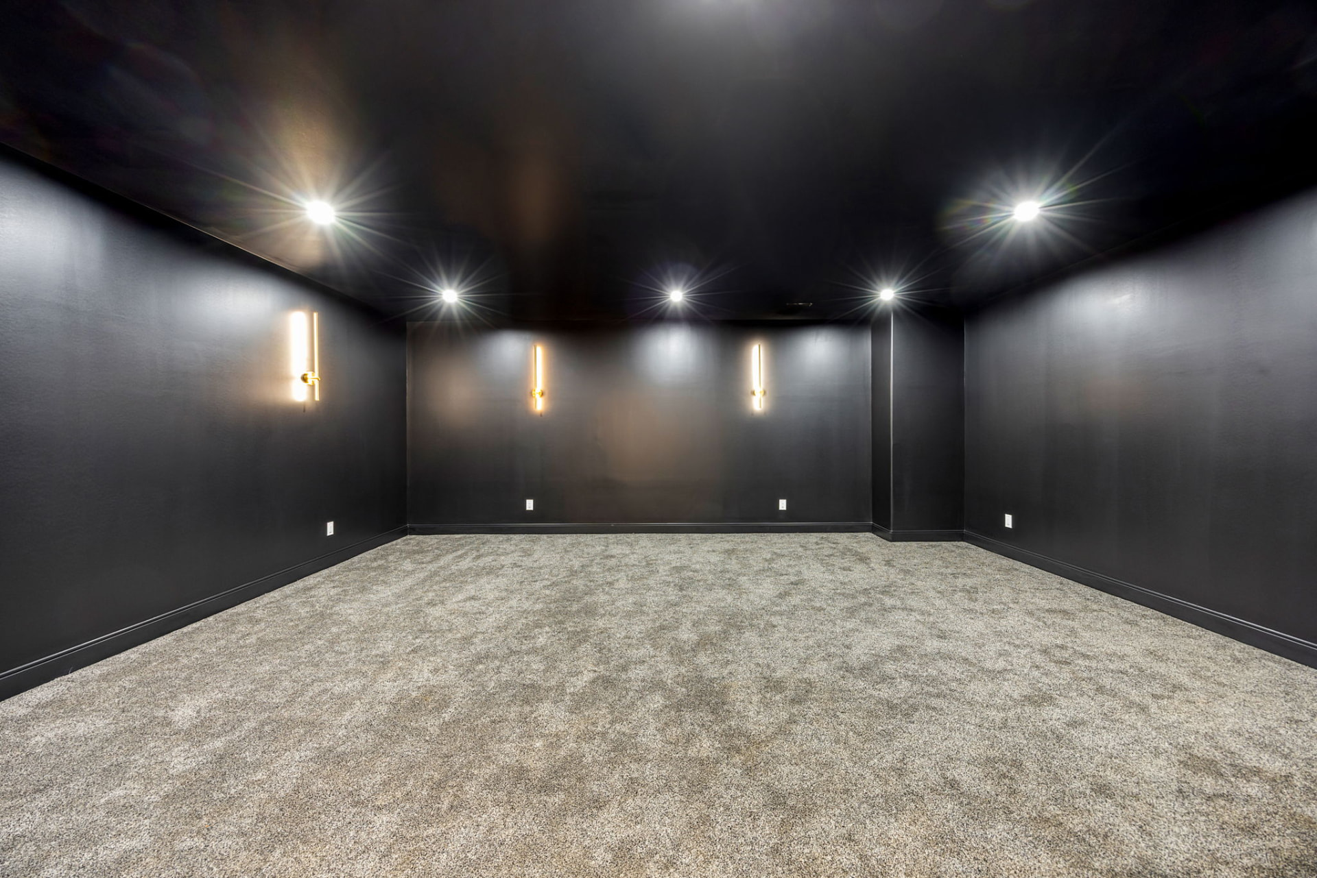Home theatre with black walls and brass sconces